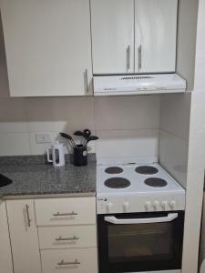 a kitchen with a stove and white cabinets at Excellent Monoambiente in Santos Lugares +9 photos