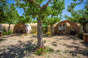 a house with a tree and flowers in the yard at Camping Clarà in Torredembarra
