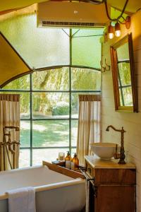 a bathroom with a tub and a sink and a window at Don Aniceto Lodges & Glamping in Luján