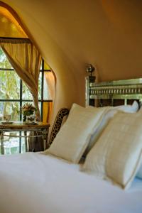 a bedroom with a bed with white pillows and a window at Don Aniceto Lodges & Glamping in Luján