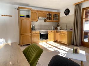 a kitchen with wooden cabinets and a table with green chairs at Rüf Stefanie in Au im Bregenzerwald +22 photos