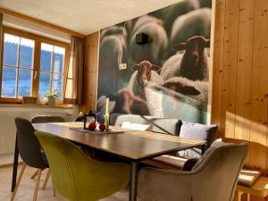 a dining room with a table and a painting of sheep at Rüf Stefanie in Au im Bregenzerwald