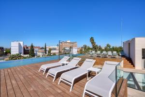 a group of white lounge chairs on a roof at Hotel Ybarra Sevilla in Seville