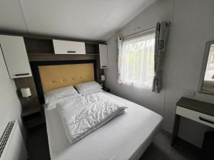 a small bedroom with a white bed and a window at 820 Ocean View, Lydstep Haven Beach in Tenby