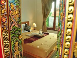 a bedroom with a bed with a painting on the wall at Angga Homestay in Ubud