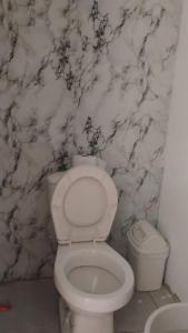 a white toilet in a bathroom with a marble wall at Pikua Beach Baru in Playa Blanca +27 photos