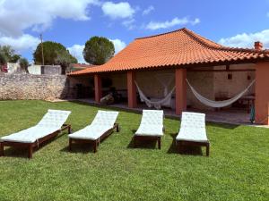 a group of chairs sitting in the grass near a building at Casa da Mata in Torres Novas