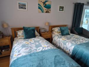 a bedroom with two beds with blue comforters at Little Orchard Apartment in Yate
