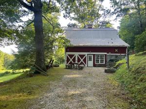 a red and white barn with a tree in front of it at Charming Rustic Barn in Spruce Pine