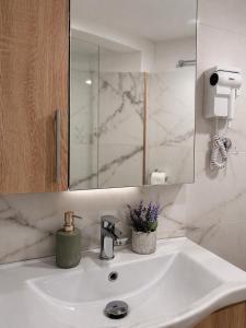 a bathroom with a sink with a mirror and flowers at Olive tree studio ,Corfu Town in Ágios Rókkos
