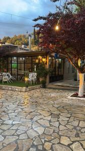 a building with a tree and a stone patio at The Millers Room at Neromilos Watermill in Monastirákion
