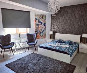 a bedroom with a bed and two chairs and a table at Premier Apartaments by Twin Residence in Mamaia