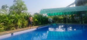a man standing on the edge of a swimming pool at Bhogwal farm house in Karjat