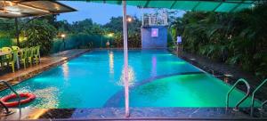an empty swimming pool with an umbrella in a backyard at Bhogwal farm house in Karjat