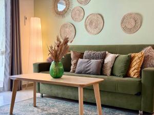 a living room with a green couch and a table at Coastal 2BR Apt in Mackenzie Steps from Beach by Cyprus Horizons in Scala
