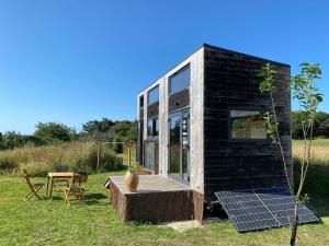 a black tiny house with a solar panel on a field at La tiny house Low Tech in Cléder