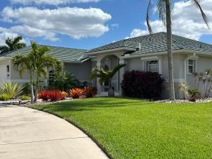 a house with a green lawn and palm trees at Salted Sunset at Punta Gorda Isles in Punta Gorda