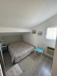 a bedroom with a bed and a chair in it at Maison Maubuisson proche du lac de Carcans in Carcans