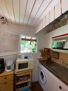 a kitchen with a washing machine and a microwave at Maison Maubuisson proche du lac de Carcans in Carcans +9 photos