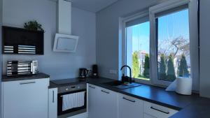 a kitchen with white cabinets and a large window at Bele Lofts in Karmėlava +4 photos