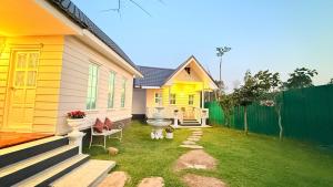 a yellow house with a yard next to a fence at I Hug Homestay ไอฮัก ที่พักเชียงใหม่ in Ban Thap Dua