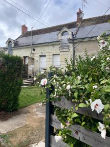 a house with flowers in front of a fence at Le Petit Bréhémontais in Bréhémont +3 photos