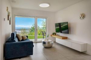 a living room with a blue couch and a tv at Apartment La Lita Panoramic Sea View Parking Self Checkin in Šmarje
