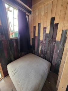 a bed in a room with a wooden wall at Ardennen Kotje in Durbuy