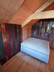 a small bed in a room with wooden walls at Ardennen Kotje in Durbuy