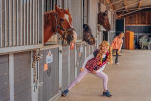 a young girl standing in a barn with a horse at Bauernhof Lafrenz, Relax Bungalow Küstenperle in Fehmarn