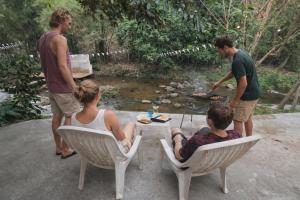 a group of people sitting around a table near a creek at 1000 Stars Riverside Hostel in Ban Khrae Yao Doi Bo
