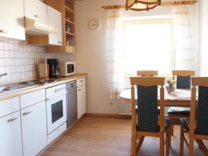 a kitchen with white cabinets and a table and a window at Ferienwohnung Arber in Dösingerried