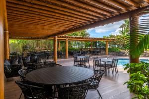 a patio with tables and chairs and a pool at Quinta do Sol Praia Hotel in Porto Seguro