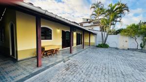 a yellow building with a table and chairs on a brick patio at Casa Lar Doce Mar Juquehy in São Sebastião
