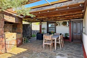 a patio with a table and chairs under a wooden pergola at Casa El Colmenero in Garafía