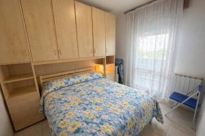 a bedroom with a bed with a floral bedspread and a window at Residence Patty in Caorle