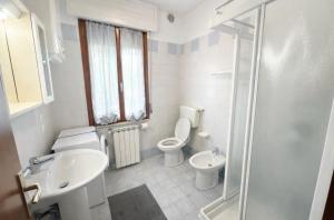 a white bathroom with a toilet and a sink at Residence Patty in Caorle
