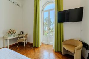 a bedroom with a bed and a desk and a window at Promenade Maison de Charme in Sanremo