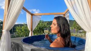 a woman in a hot tub with a glass of wine at Luz de Cabana in Santo Amaro da Imperatriz