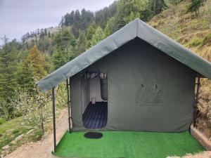 a tent that is on a hill with a green floor at New Kufari Apple Valley camping in Shimla
