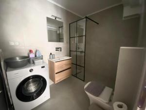a bathroom with a washing machine and a sink at Nikol's central suite 2 in Nea Peramos +15 photos