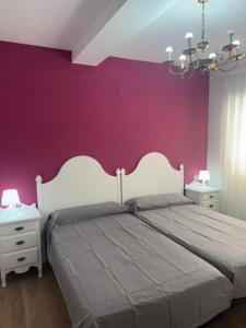 a bedroom with a white bed and purple wall at Dalia Somhome in Peniscola