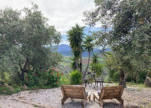 two wooden chairs and a table in a garden at Casa del Sueño - Casitas met uitzicht in Alora +46 photos