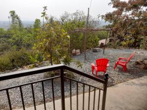 two red chairs and a swing on a porch at Wonderville Ensuite Rooms in Cuncolim