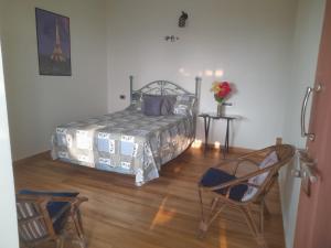 a bedroom with a bed and a chair and a table at Wonderville Ensuite Rooms in Cuncolim