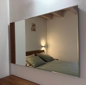 a mirror reflecting a bed in a bedroom at FLO Homestay in Levico Terme