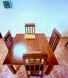 a wooden dining table with four chairs and a clock at Garden Cottage Homestay BB in Wattala +11 photos