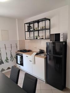 a kitchen with a black refrigerator and white cabinets at SAN MARKO 2 in Lovran