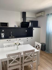 a kitchen with a white table and chairs and a table and a kitchen at House Magdic Plitvice in Grabovac