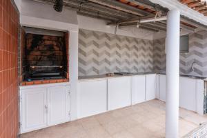 a kitchen with white cabinets and a brick wall at Vivenda Prazeres in Sesimbra